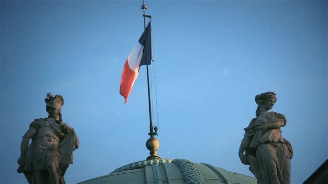 Flag of France Waving Proudly Among Sculptures Over an Old Building in Paris. The Palais de la L&eacute;gion d'honneur (French for "Palace of the Legion of Honour").
