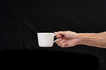 Man hand holding white coffee cup on black background