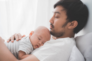 asian cute baby boy sleeping on father's chest in the bedroom