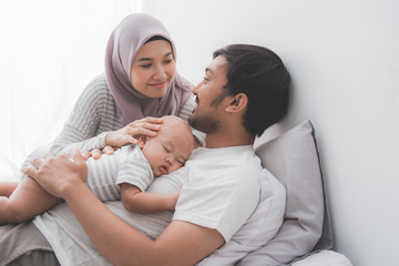 lovely young muslim parent with their newborn baby enjoy time together playing at home