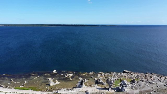 Aerial pull back of famous stone rauk at waterfront in Gotland, Sweden