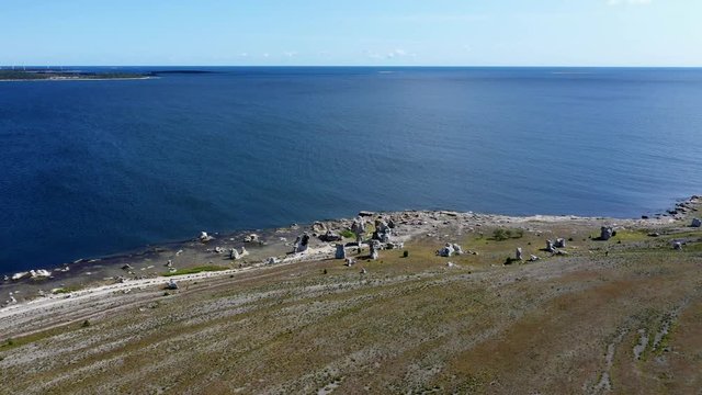 Cinematic view of stone rauk at waterfront, Gotland island in Sweden, Circling aerial shot