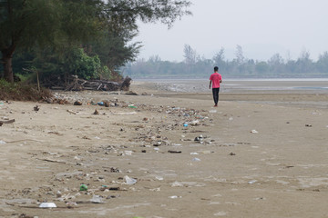 Lok Kawi, Kota Kinabalu, Sabah, Malaysia - September 08, 2019:  Unidentified boy is running on a polluted beach. The beach is full garbage that was washed up from the ocean to the shore. 
