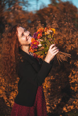 Red haired woman on autumn background. Fashion portrait of red haired woman.
