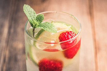 Sweet summer cocktail with raspberry and lime on the rustic background. Selective focus. Shallow depth of field.