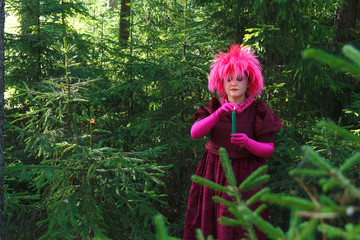 Forest witch in purple clothes conjures among the forest with candles.