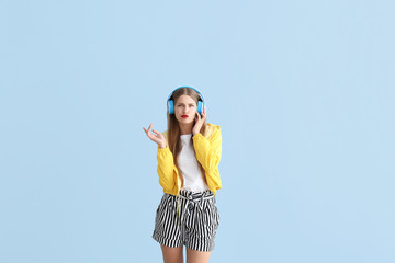 Thoughtful young woman listening to music on color background