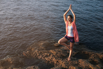 Young woman practicing yoga near river