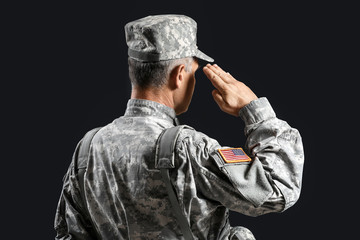 Saluting male soldier on dark background