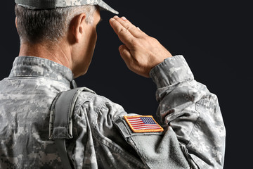 Saluting male soldier on dark background
