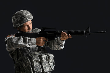 Fototapeta premium Mature male soldier aiming from assault rifle on dark background
