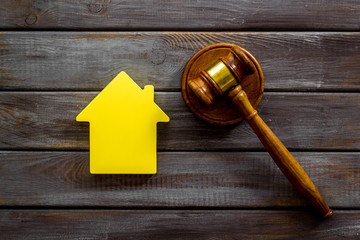 Inheritance of the house concept with figure and gavel on wooden background top view