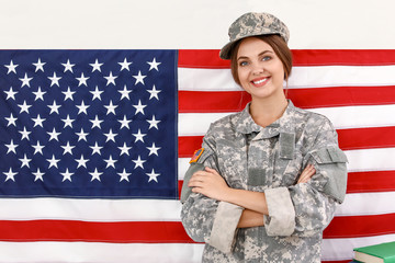 Young female soldier near wall with USA flag in headquarters building