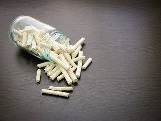 Kashk ( qurt, kurut, gurt or qurut) are poured from a glass jar on dark wooden surface.