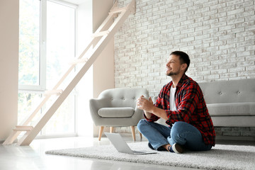 Man with laptop and cup of tea relaxing at home