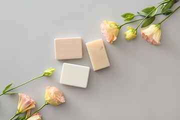 Different soap with flowers on grey background