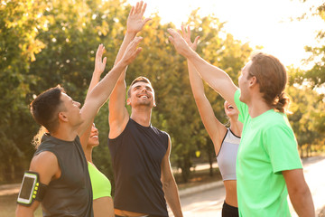 Obraz premium Group of sporty young people putting hands together outdoors