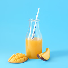 Bottle of fresh mango juice on color background