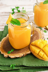 Mason jars of fresh mango juice on table