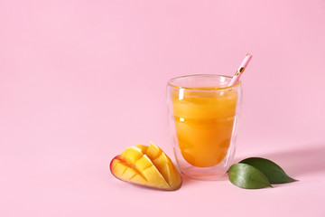 Glass of fresh mango juice on color background