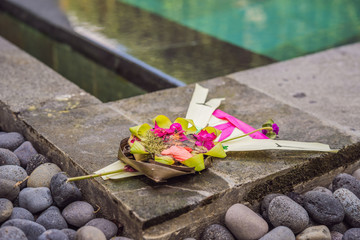 Traditional balinese offerings to gods in Bali with flowers and aromatic sticks