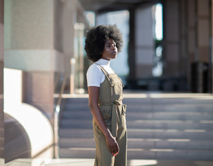 Fashionable African American girl in downtown wearing fancy overalls and white turtleneck
