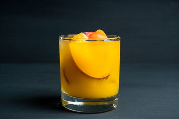 Fresh peach beverage in old fashioned glass on the rustic background. Selective focus.