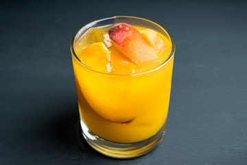 Fresh peach beverage in old fashioned glass on the rustic background. Selective focus.