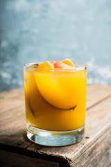 Fresh peach beverage in old fashioned glass on the rustic background. Selective focus.