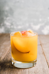 Fresh peach beverage in old fashioned glass on the rustic background. Selective focus.