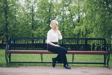 entrepreneur talking on the phone in the Park. Blonde hair Bob works outside. businesswoman with smartphone