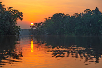 Reflection of a sunset by a lagoon inside the Amazon Rainforest Basin. The Amazon river basin...
