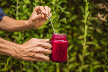 Dragon fruit smoothie with steel drinking straw in male hands