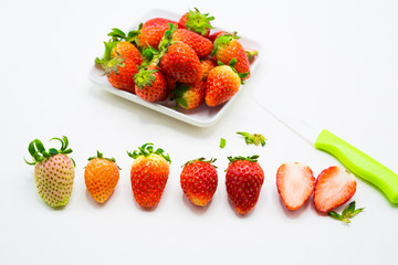 fresh strawberry with white plate and knife on white cutting board