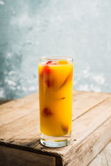 Fresh peach beverage with red ripe raspberry on the rustic background. Selective focus.