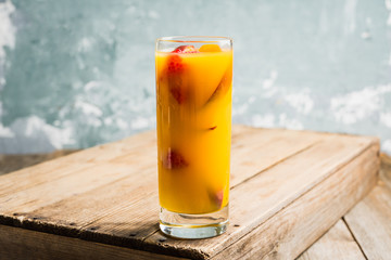 Fresh peach beverage with red ripe raspberry on the rustic background. Selective focus.