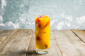 Fresh peach beverage with red ripe raspberry on the rustic background. Selective focus.