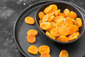 Dried apricots in a black plate on a black table