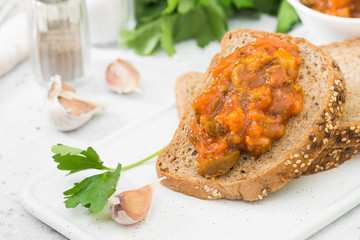 Bread with vegetable caviar on a white tray on a light gray background