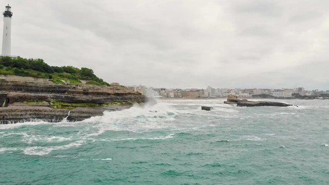 Aerial shot of Biarritz Beach Resort Light House in cloudy day with big Waves crushing on Cliffs - Basque Country South West of France