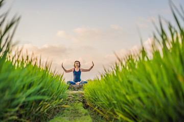 Young woman practice yoga outdoor in rice fields in the morning during wellness retreat in Bali