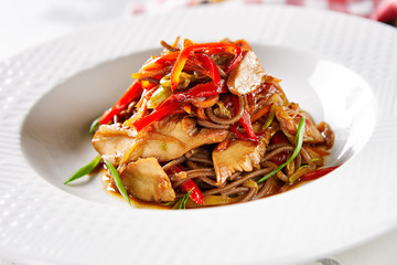 Asian Style Soba with Chicken and Vegetables on Elegant Restaurant White Plate Close Up. Traditional Japanese Buckwheat Noodles Zaru with Poultry Meat, Greens and Vegetables Top View