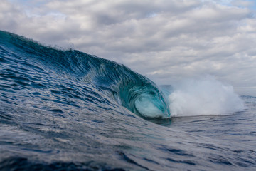 huge wave crashing on a reef with a dark moody sky in the background