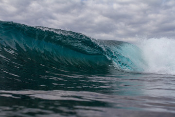 perfect wave crashing on a reef with dark and moody clouds