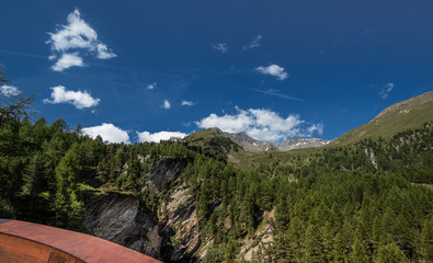 Fototapeta na wymiar Panorama Hochgebirge mit Fels und Schutzhütte vor blauem Himmel und Gebirgskamm