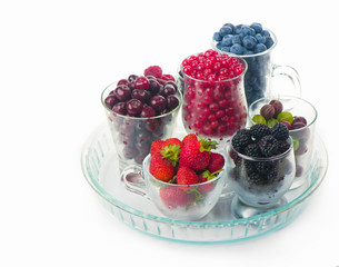 different summer berries red currant, gooseberry, raspberry in glass trays. sorted by type. superfoods from the garden