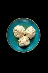 khinkali on a colored plate on a black background