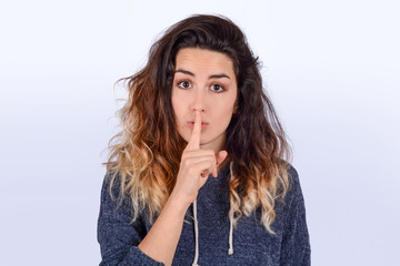Close up of young woman making silence gesture.