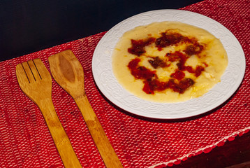 Plate of polenta, organic Italian food with milk, pumpkin and cheese, and red sauce with tomato and fresh basil. Horizontal studio shot.