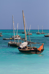 Obraz premium traditional african sailboats parked in a turquoise blue bay